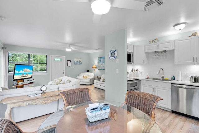 dining space with a ceiling fan, light wood-type flooring, and visible vents