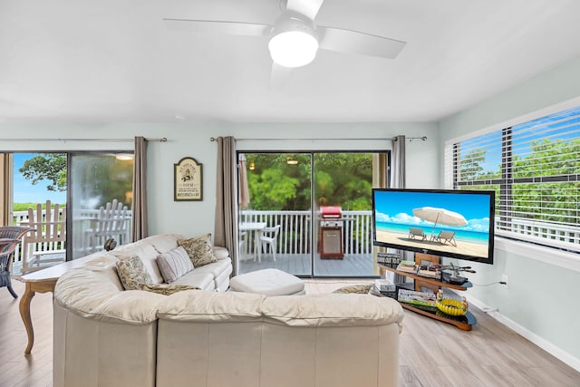 living room featuring a ceiling fan, baseboards, and light wood finished floors