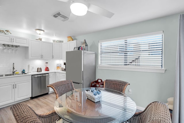 kitchen featuring stainless steel appliances, light countertops, visible vents, white cabinets, and a sink