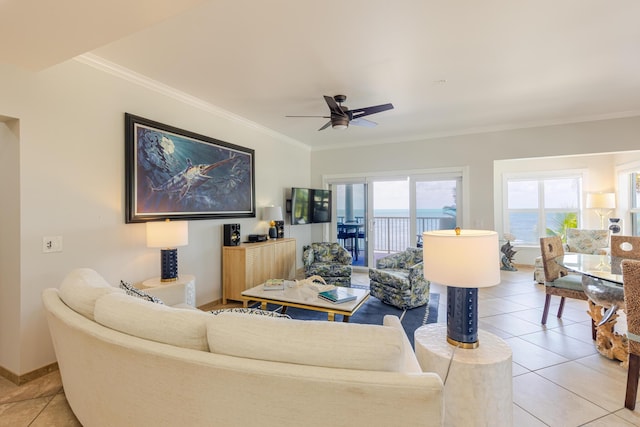 living area featuring baseboards, ornamental molding, ceiling fan, and light tile patterned floors