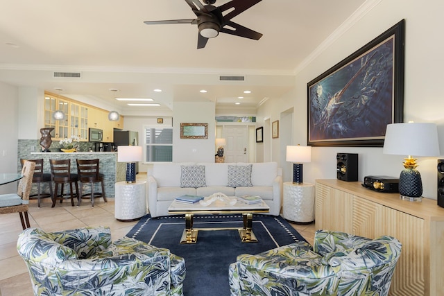 living area with crown molding, light tile patterned flooring, ceiling fan, and visible vents