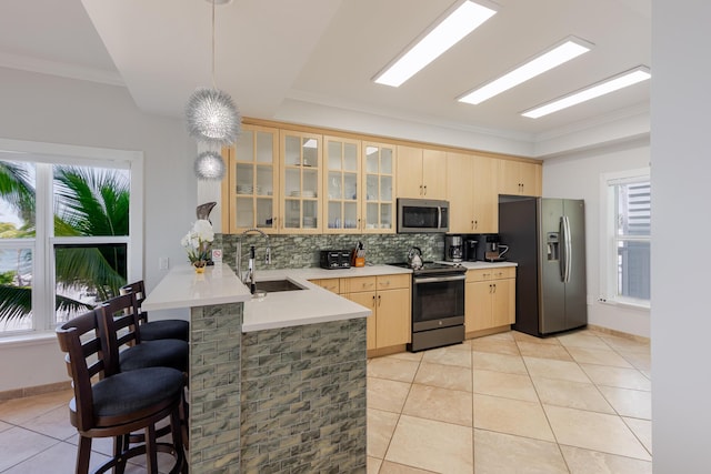 kitchen featuring a peninsula, light tile patterned flooring, light brown cabinets, a sink, and stainless steel appliances