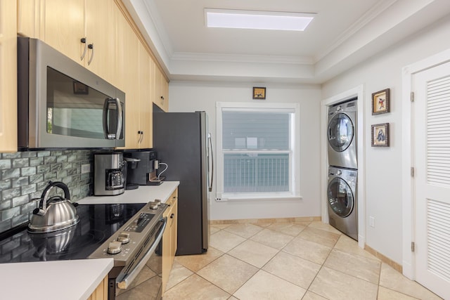 kitchen featuring stacked washer / dryer, crown molding, appliances with stainless steel finishes, tasteful backsplash, and light brown cabinetry