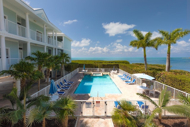 community pool with a water view, fence private yard, and a patio area
