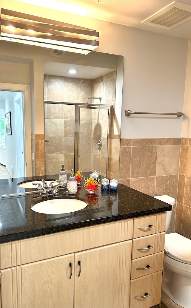 full bath with visible vents, tile walls, a stall shower, vanity, and toilet