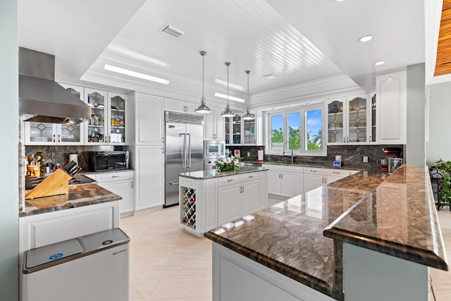 kitchen featuring island range hood, a kitchen island, glass insert cabinets, and built in appliances