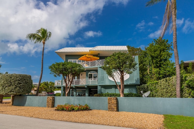 view of front facade featuring a tiled roof, a balcony, and stucco siding