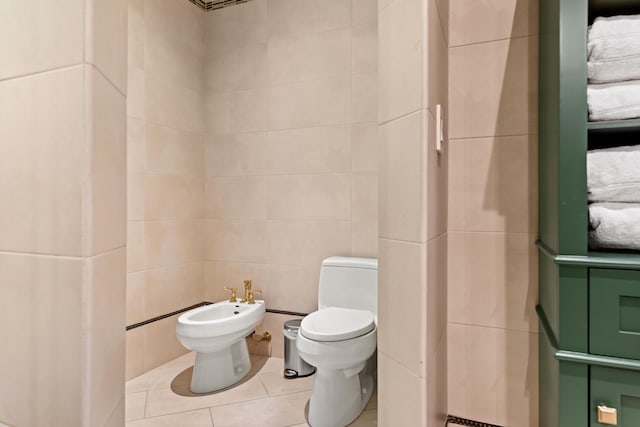 bathroom with toilet, a bidet, tile patterned flooring, and tile walls