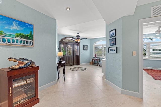 foyer featuring a wealth of natural light, visible vents, ceiling fan, and baseboards