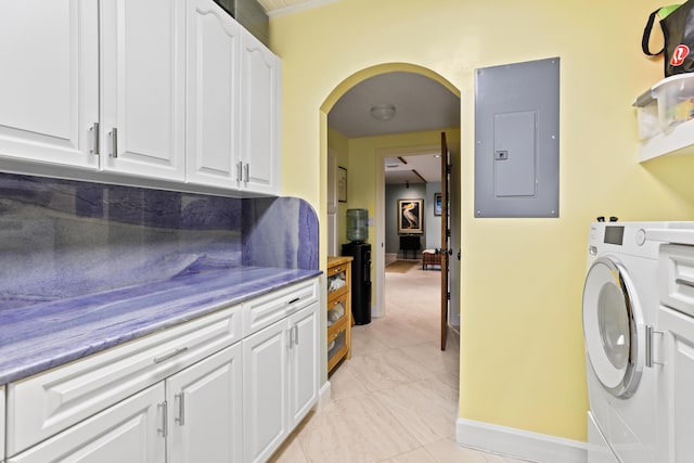 washroom featuring arched walkways, baseboards, cabinet space, electric panel, and washer / dryer