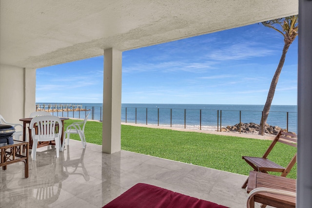 view of patio / terrace featuring a view of the beach, a water view, and fence