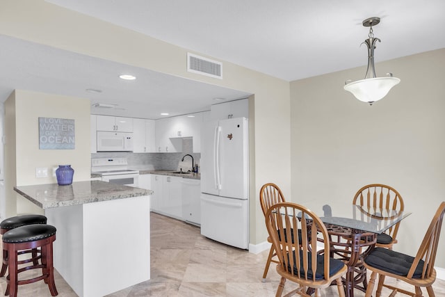 kitchen featuring a peninsula, white appliances, visible vents, white cabinetry, and decorative light fixtures