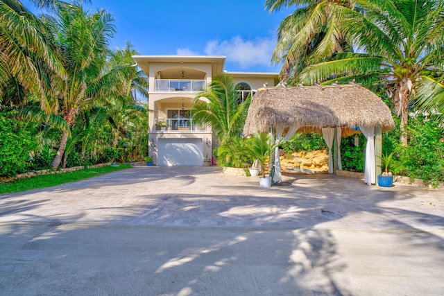 view of front of home featuring decorative driveway, an attached garage, a balcony, and stucco siding