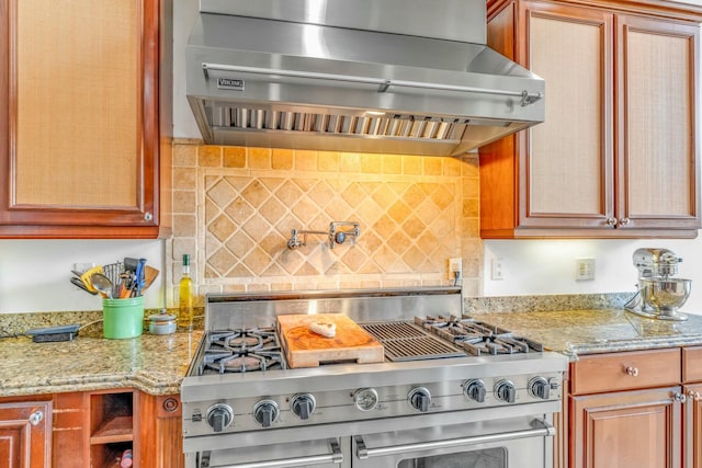 kitchen with tasteful backsplash, high end stainless steel range oven, light stone counters, and exhaust hood