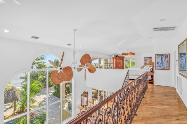 corridor featuring light wood-style flooring, visible vents, and a healthy amount of sunlight