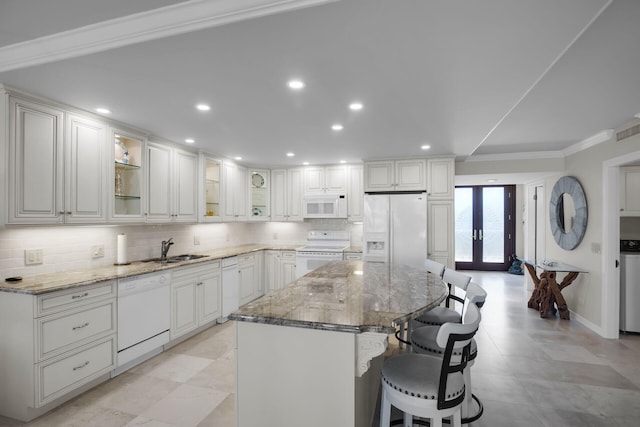 kitchen with white appliances, ornamental molding, a breakfast bar, a sink, and decorative backsplash