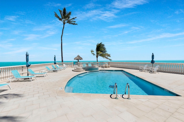 pool with a water view, a patio, and a hot tub