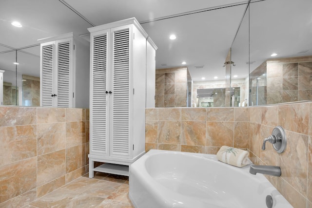 bathroom with a stall shower, a closet, a garden tub, and tile walls