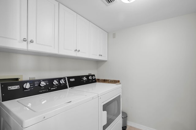 clothes washing area with cabinet space, visible vents, washing machine and clothes dryer, and baseboards