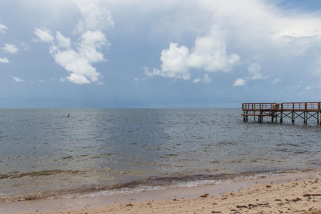 view of dock with a beach view and a water view