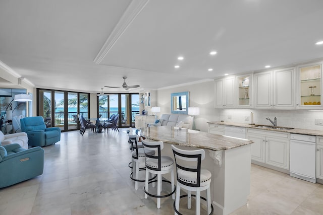 kitchen with open floor plan, a sink, crown molding, and decorative backsplash
