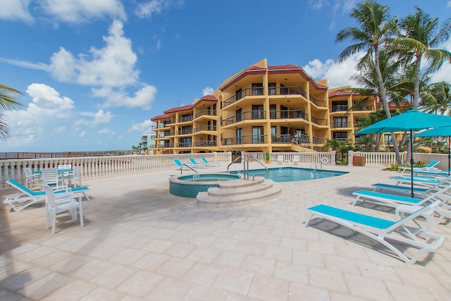 pool with a patio area and a community hot tub