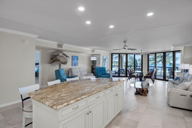 kitchen featuring open floor plan, light stone countertops, ornamental molding, and visible vents