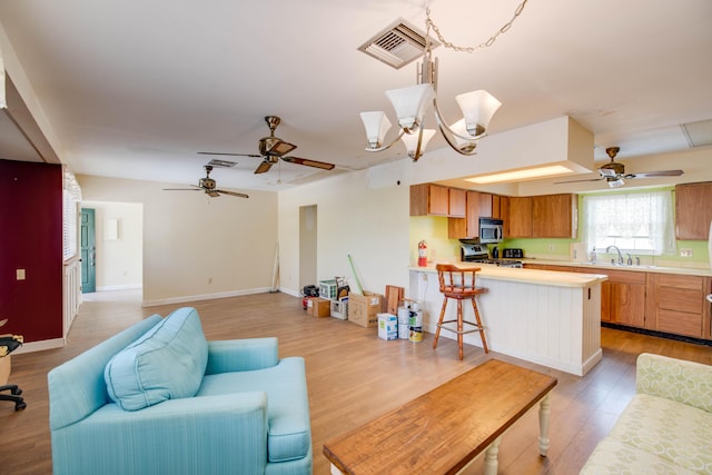 living room with a chandelier, light wood-style flooring, visible vents, and baseboards