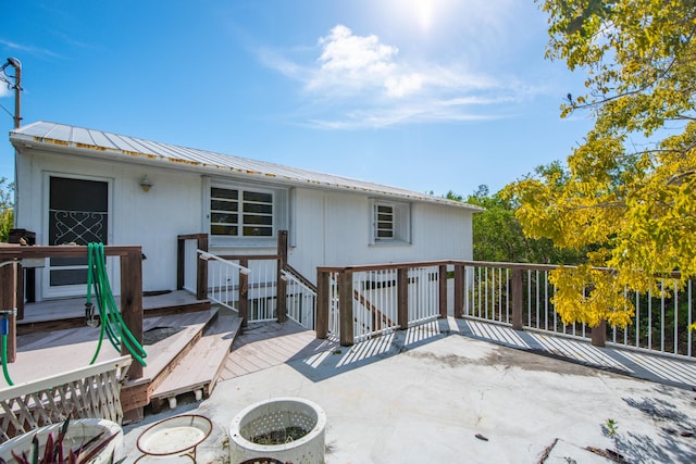 rear view of property featuring a standing seam roof, metal roof, and a deck