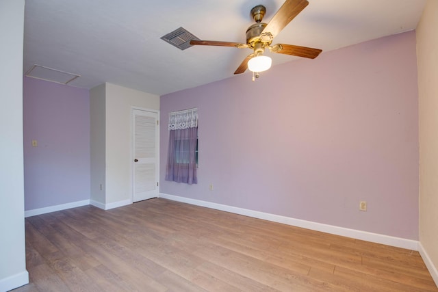 empty room featuring ceiling fan, light wood finished floors, attic access, and baseboards