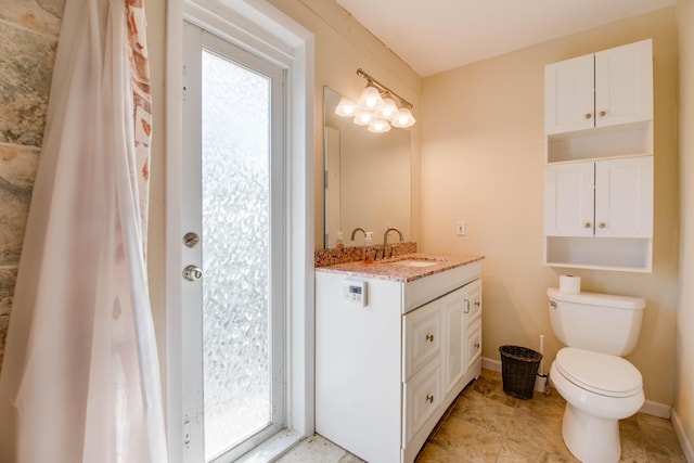 full bathroom featuring toilet, baseboards, and vanity