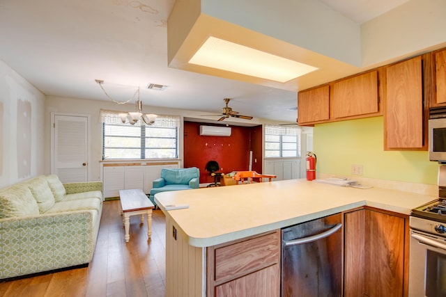 kitchen featuring stainless steel appliances, light countertops, an AC wall unit, open floor plan, and a peninsula