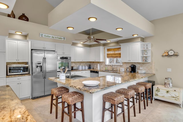 210 14th St, Key Colony, FL 33051 - kitchen with a peninsula, appliances with stainless steel finishes, decorative backsplash, and white cabinets