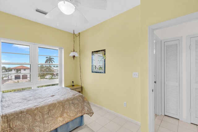 bedroom featuring light tile patterned floors, ceiling fan, visible vents, and baseboards