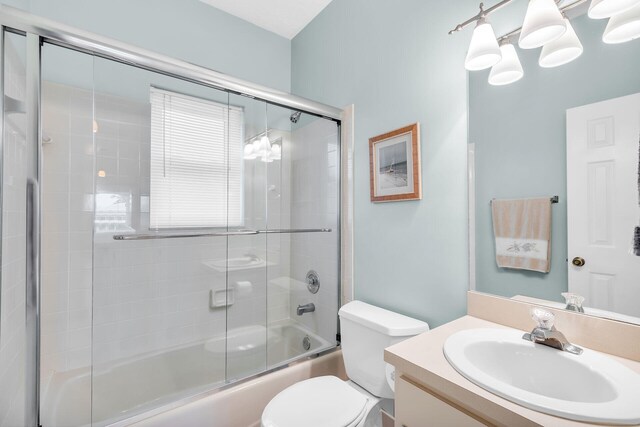 full bath featuring toilet, bath / shower combo with glass door, and vanity