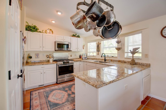 kitchen featuring a peninsula, appliances with stainless steel finishes, white cabinets, and a sink