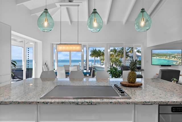 kitchen with light stone counters, stainless steel electric stovetop, beamed ceiling, and hanging light fixtures