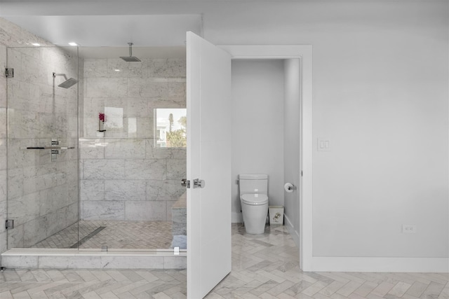 bathroom with toilet, a shower stall, and baseboards