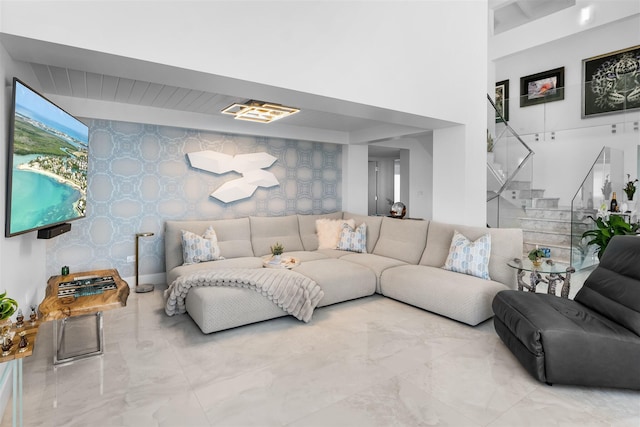 living area featuring an accent wall, marble finish floor, stairway, and wallpapered walls