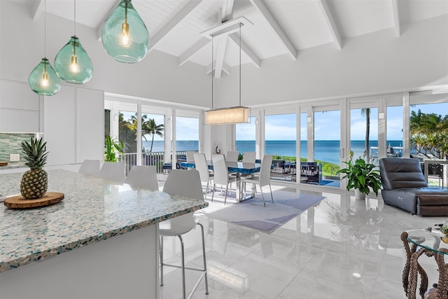 sunroom featuring a water view and vaulted ceiling with beams