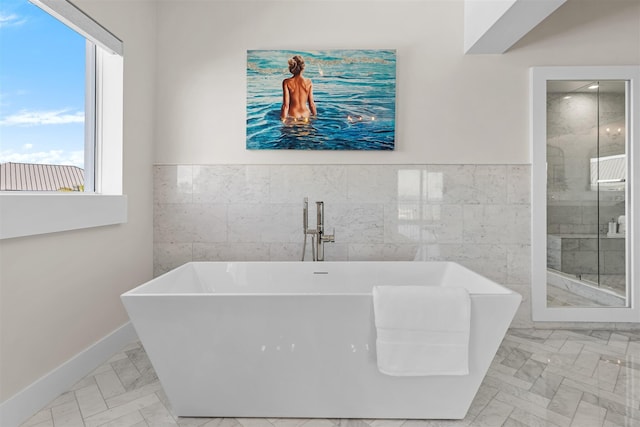 full bathroom featuring a freestanding tub, a wainscoted wall, tile walls, marble finish floor, and a shower stall