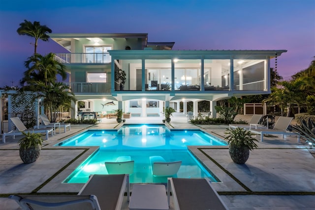 pool at dusk featuring a patio and an outdoor pool