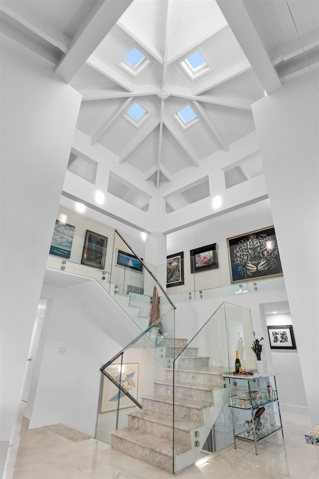 staircase with beam ceiling and a towering ceiling