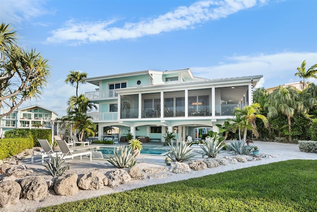 back of house with a balcony, a sunroom, an outdoor pool, and a patio