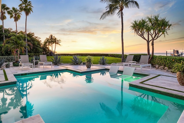 pool at dusk featuring a patio area and an outdoor pool