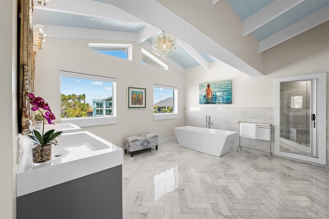 bathroom with a stall shower, vaulted ceiling with beams, an inviting chandelier, a freestanding bath, and tile walls