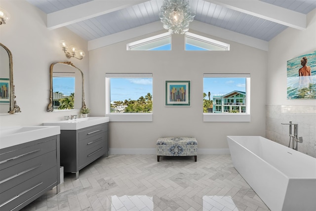 bathroom with vaulted ceiling with beams, an inviting chandelier, a freestanding bath, and vanity