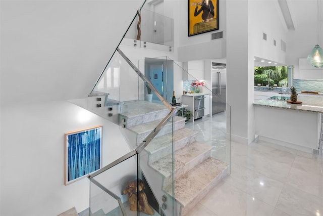 stairway featuring a towering ceiling and visible vents