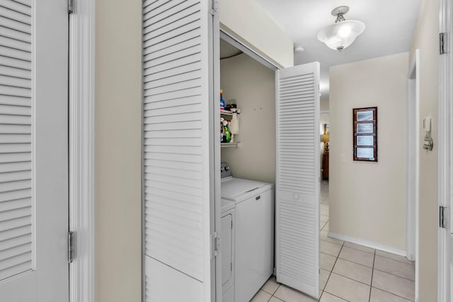 washroom with independent washer and dryer, laundry area, light tile patterned flooring, and baseboards