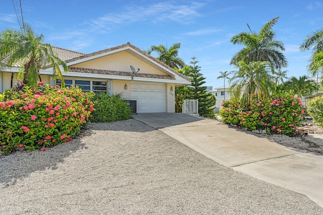 view of front facade with an attached garage, cooling unit, concrete driveway, and stucco siding